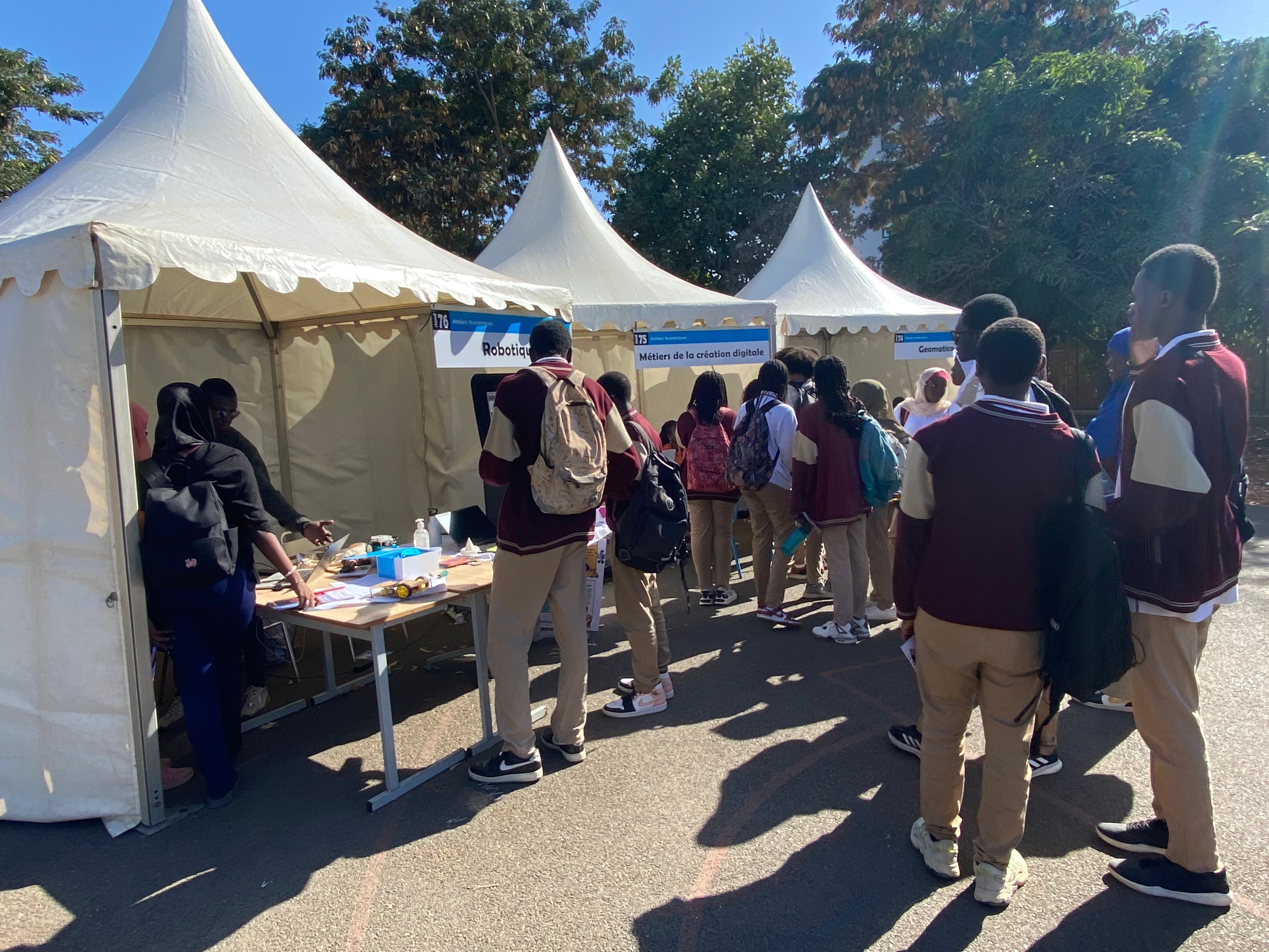 Village des ateliers numériques : les étudiants circulent entre les stands robotique, création digitale et géomatique